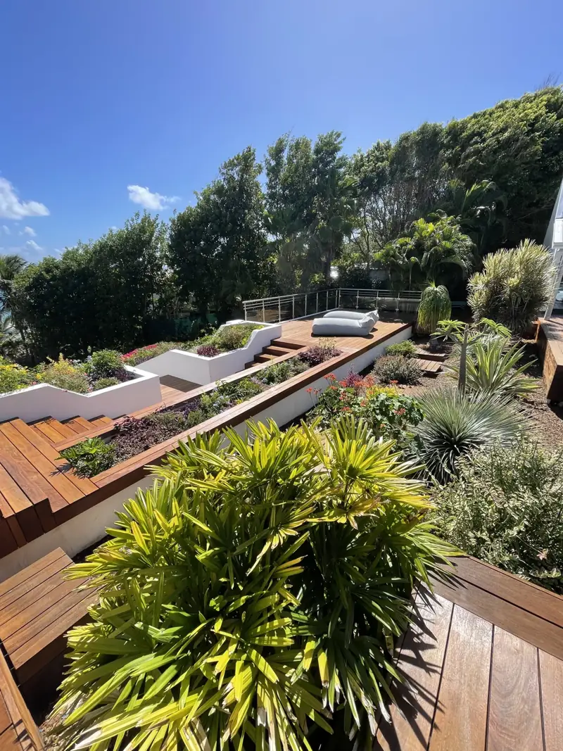 Deck en bois sur plusieurs niveaux dans un jardin tropical, photographie originale fournie par Deck Wash